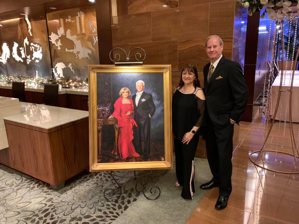 AffluentReach founders beside a donated portrait at a charitable auction event.
